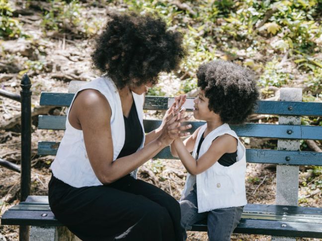 mother and child with same black and white outfits seated on a blue wooden bench