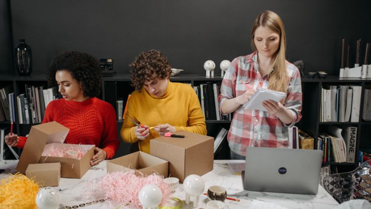 Diverse team working together, preparing packages in a creative office setting.