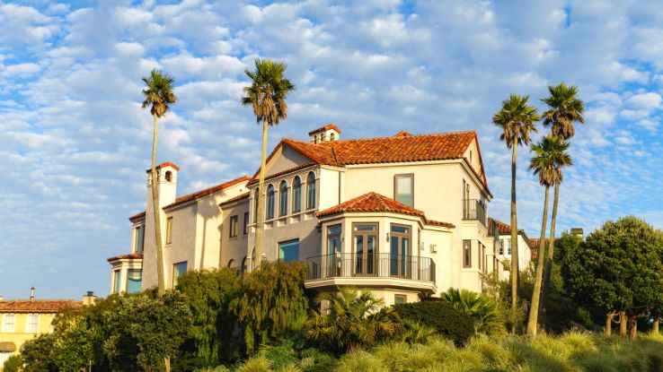 Elegant Mediterranean villa surrounded by palm trees under a bright blue sky.