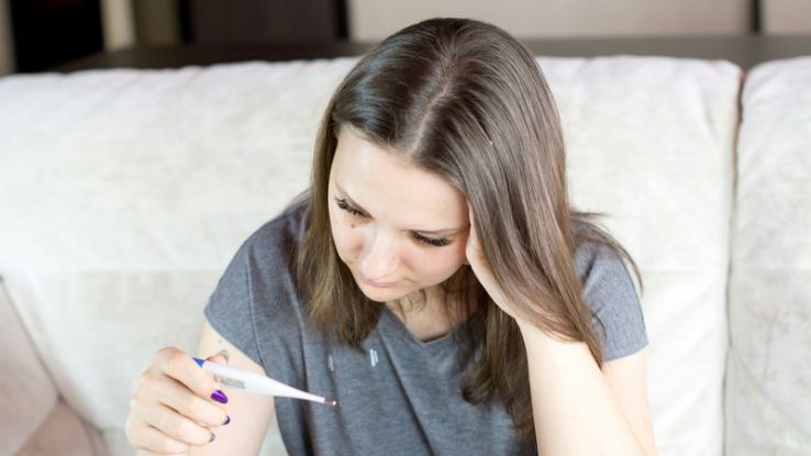 Woman holding thermometer in hands, measuring body temperature.