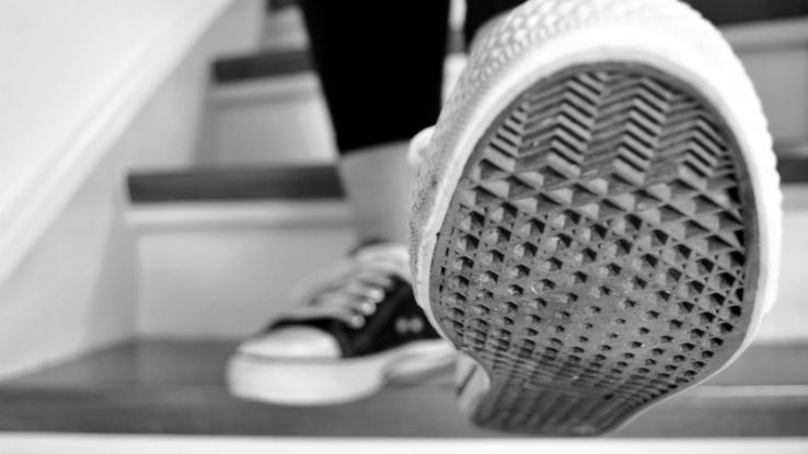 Black and white shot of sneakers ascending stairs, showcasing the sole pattern.